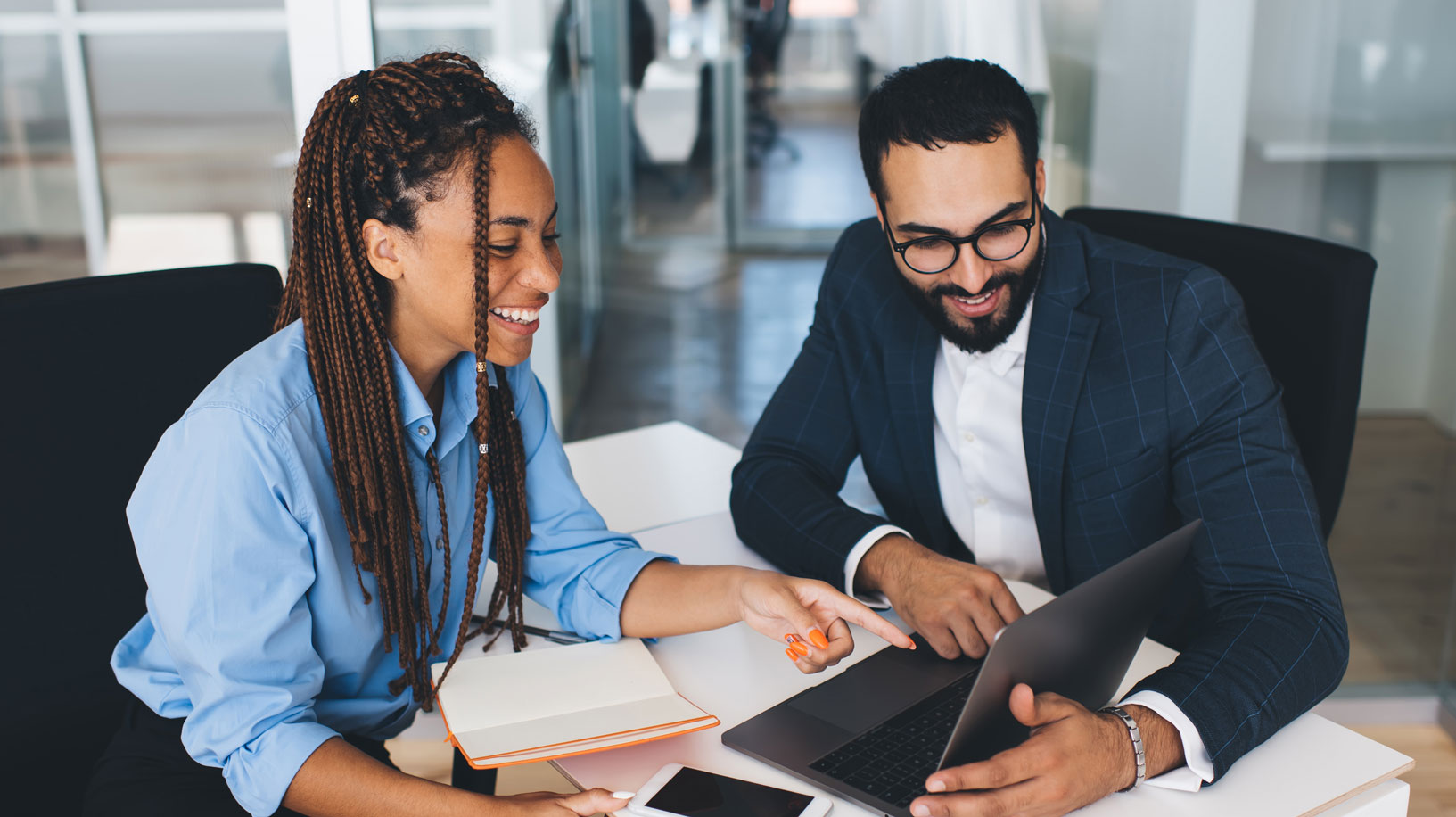 Two people - woman and man are having a meeting and pointing at the laptop screen. 
