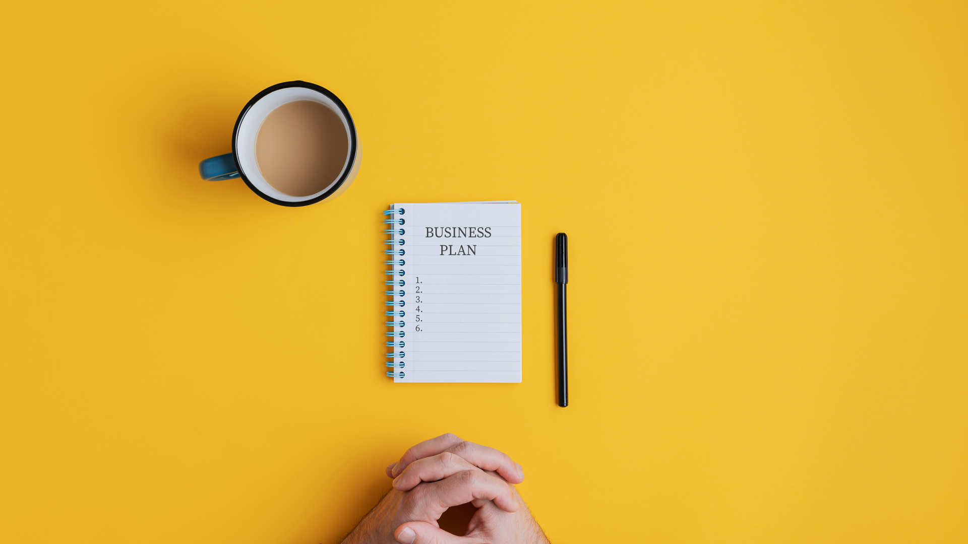 Notebook with a business plan and hands in front of the desk