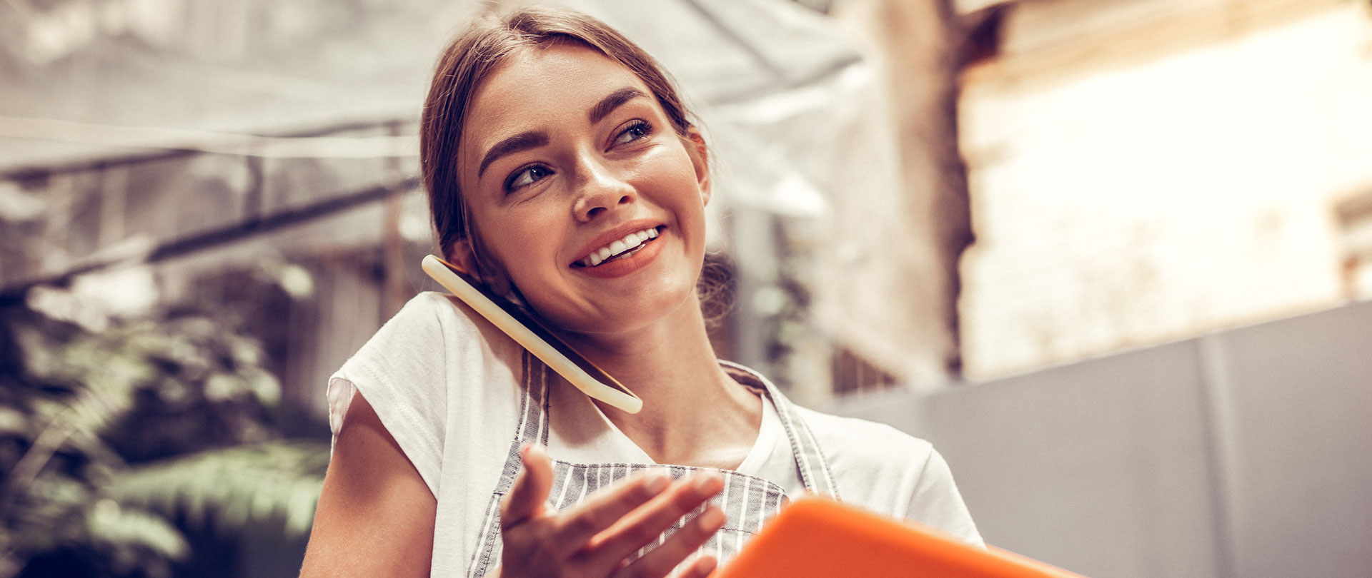 Positive happy woman having a phone conversation and holding a tablet device.