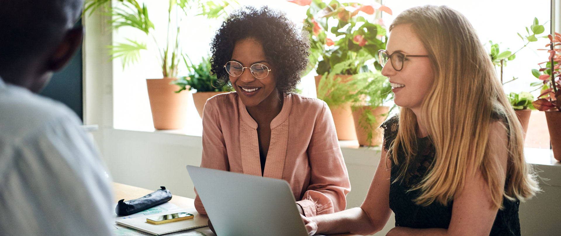 Two women sitting at a table looking at a computer