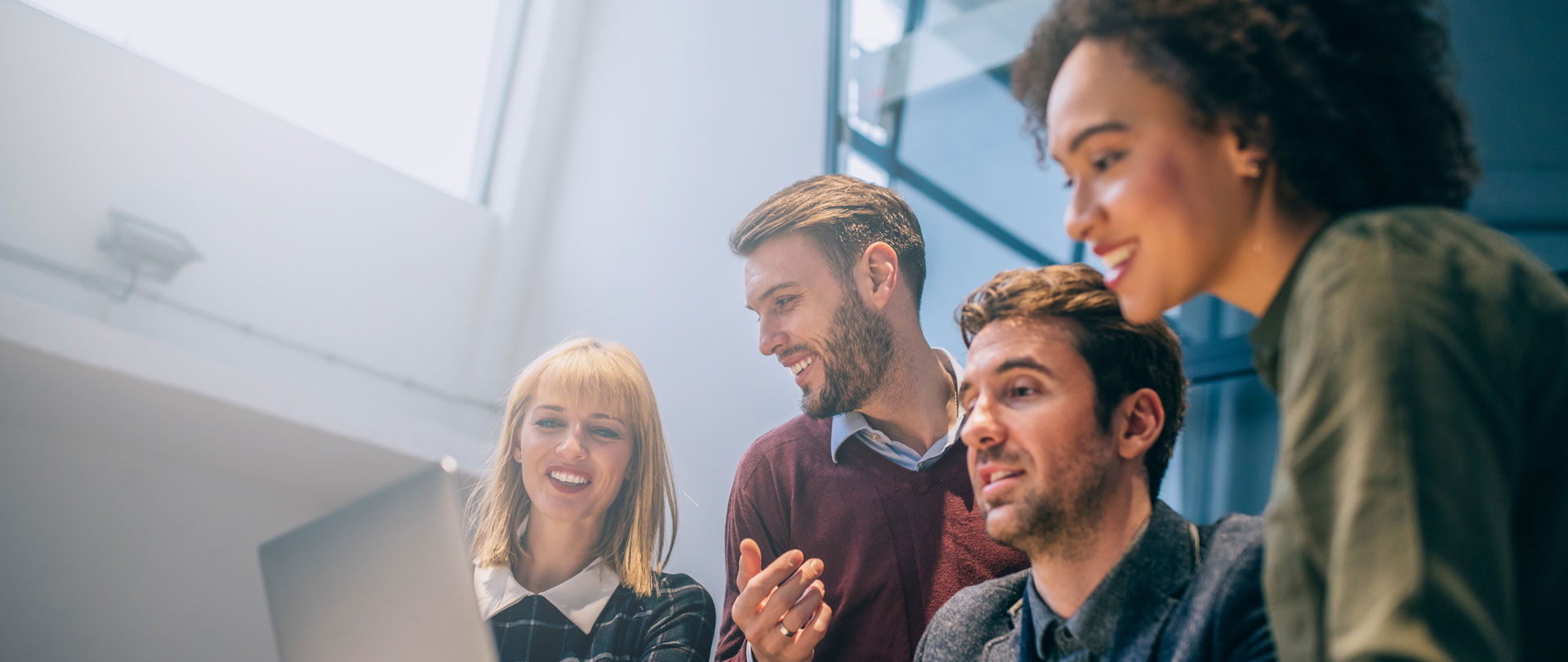 A group of people are looking at the laptop on the table.