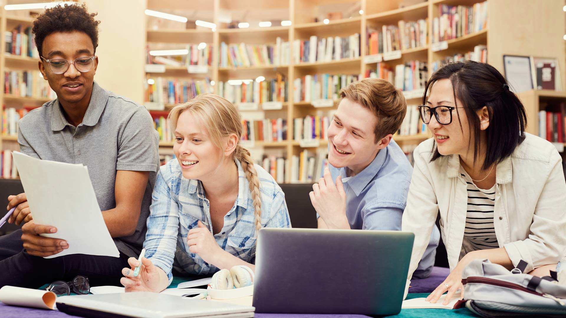 International students in the library learning with open books and laptop.